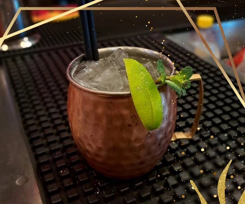 Cocktail servito in tazza di rame con lime e menta al bancone del cocktail bar a Ostia