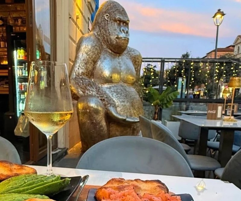 Calice di vino bianco e tagliere al tramonto nel dehors del cocktail bar a Ostia