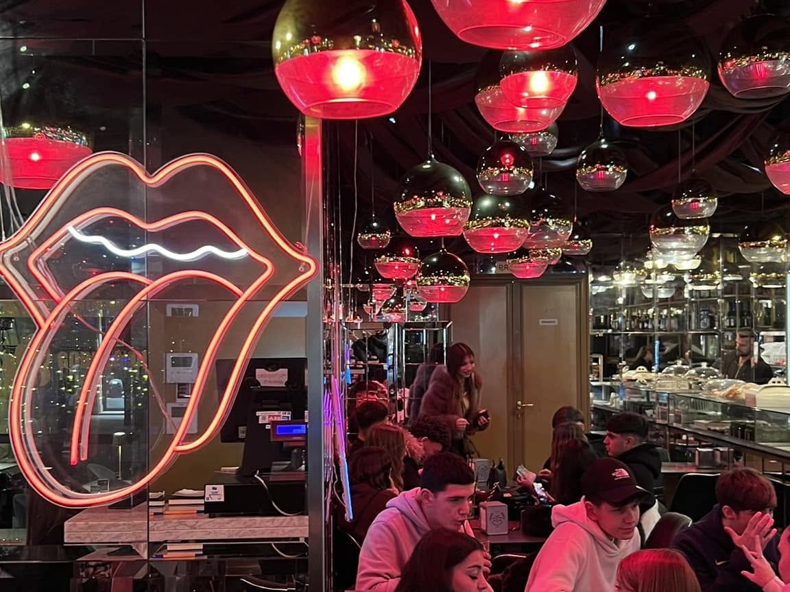 Sala interna del lounge bar a Ostia con lampadari rossi e insegna al neon